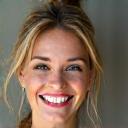 Joyful woman in her late 30s with clear skin and bright eyes.